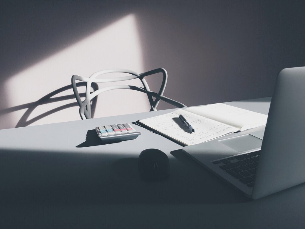 Calculadora, caderno e laptop sobre mesa de trabalho